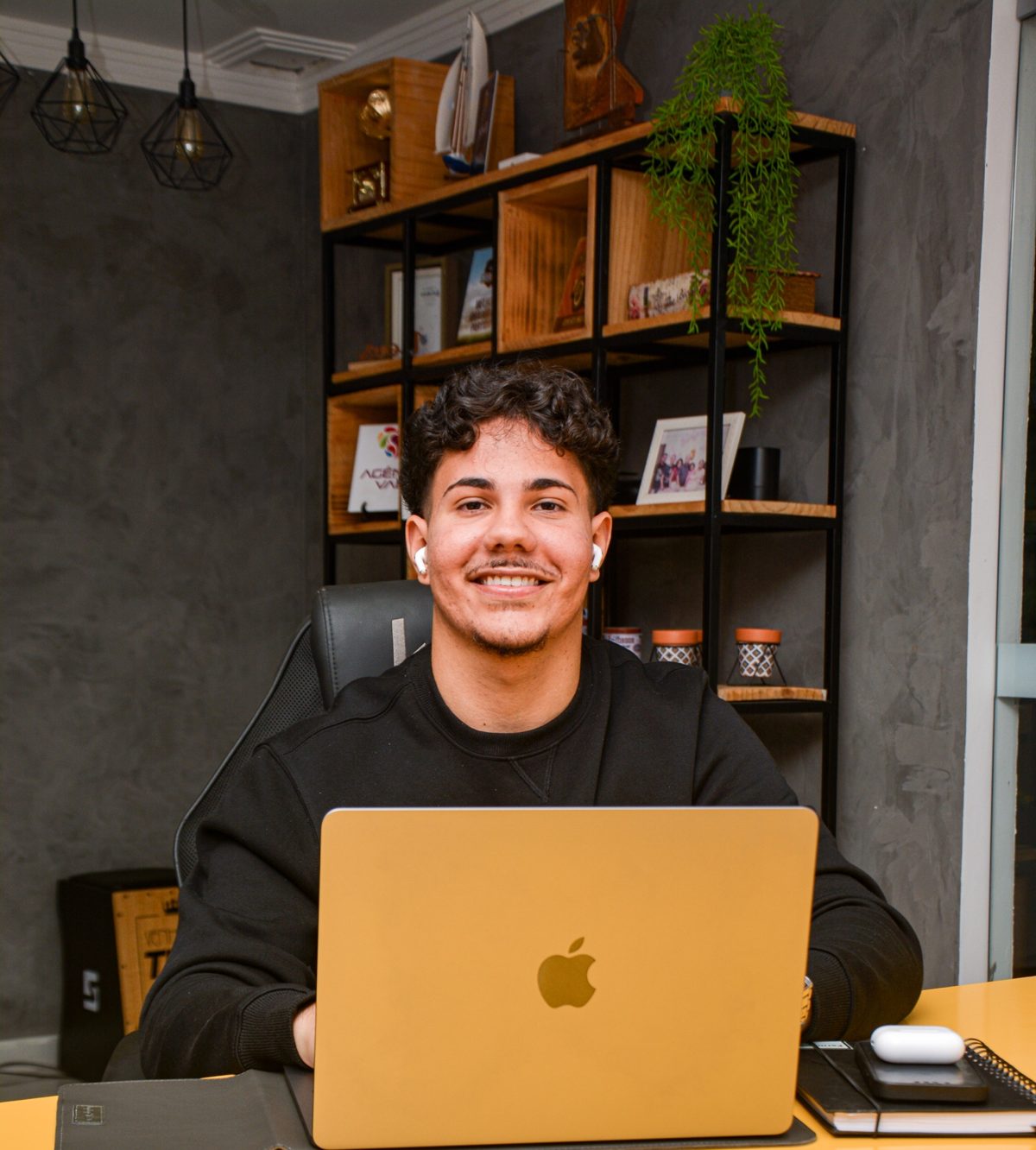 Retrato do fundador da RAVELLY, sorrindo à mesa de trabalho, diante de um notebook dourado.